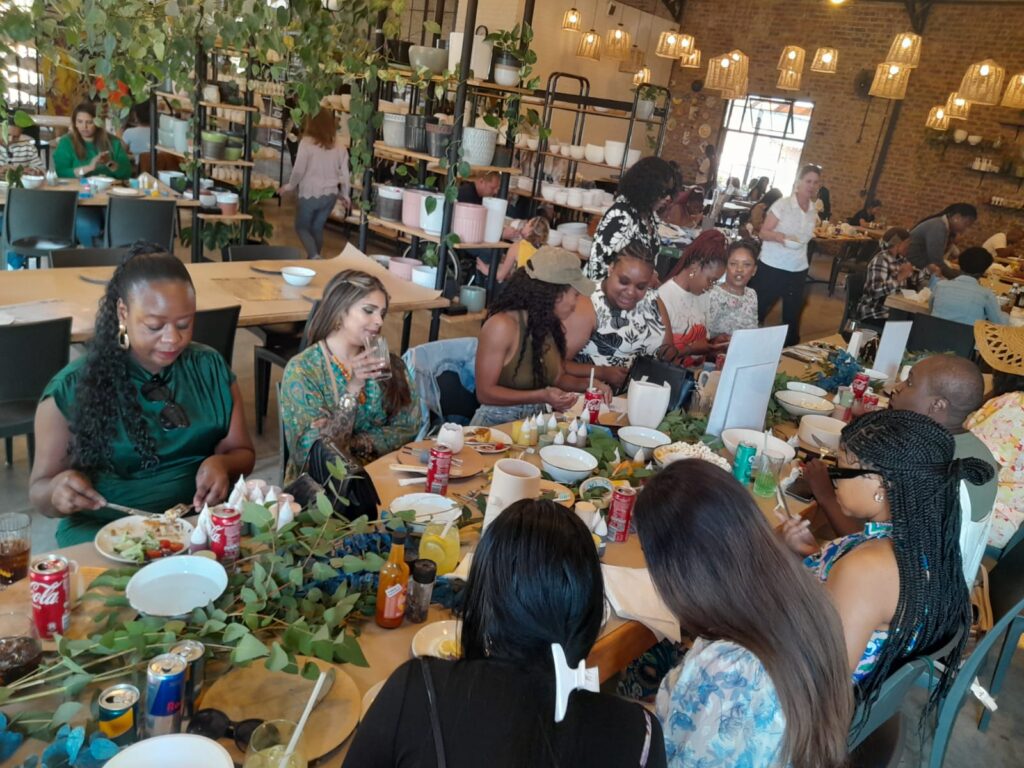 A lively indoor gathering with people seated around tables filled with food and drinks.