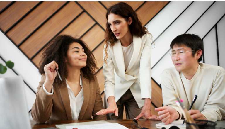 Three professionals discussing over documents at a table in a modern office.