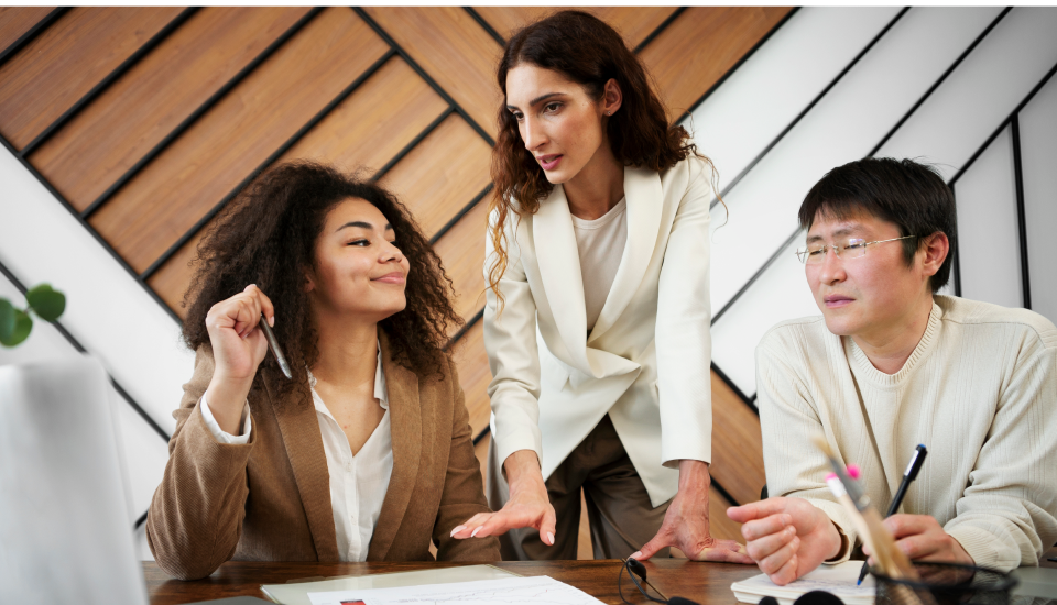 Three professionals discussing over documents at a table in a modern office.